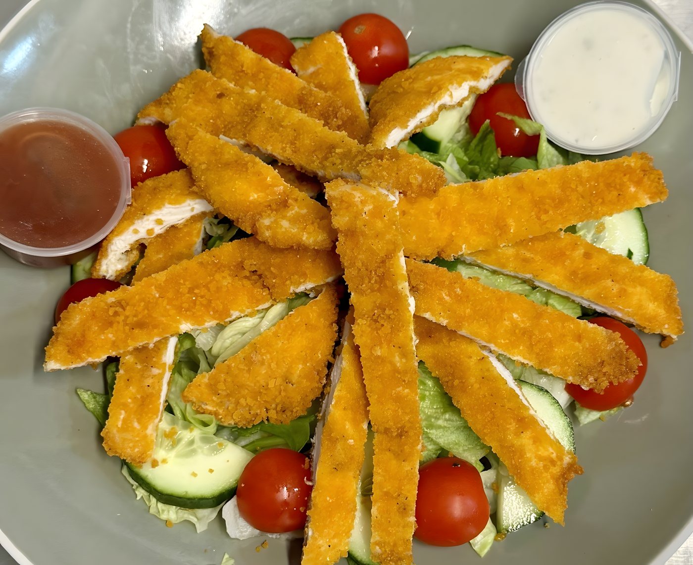 Crispy chicken strips over a fresh salad