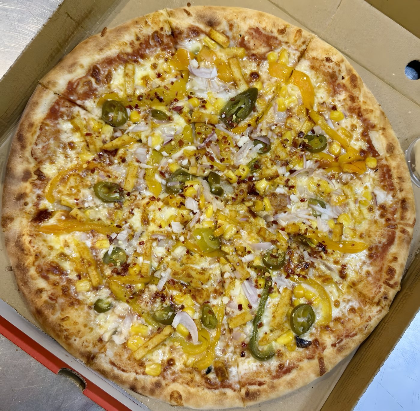 A wood-fired vegetable pizza with peppers, sweetcorn, jalapeños and red onion